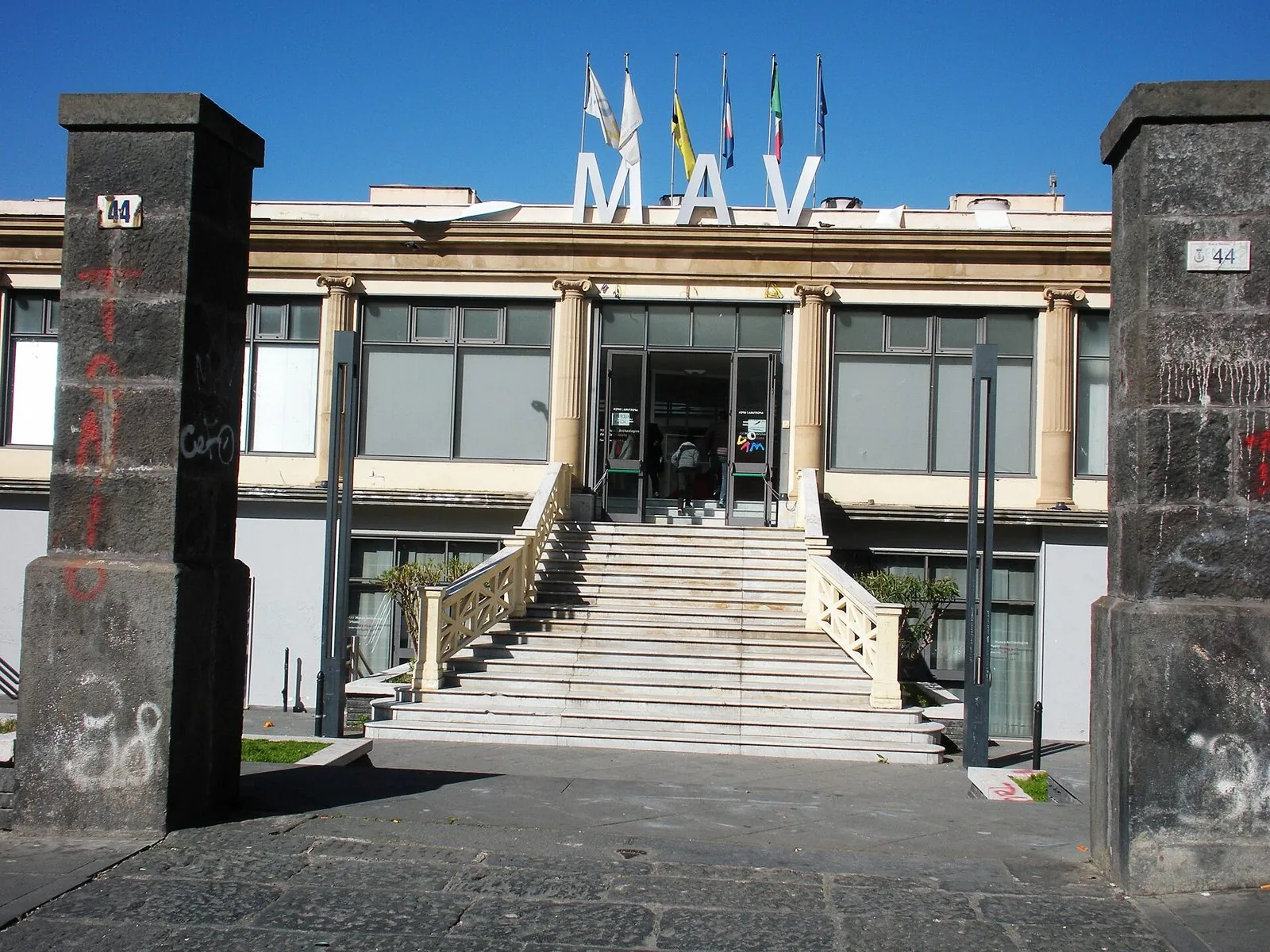 Ingresso del MAV, Museo Archeologico Virtuale di Ercolano, con la scalinata in marmo, le grandi lettere MAV sul tetto e le bandiere